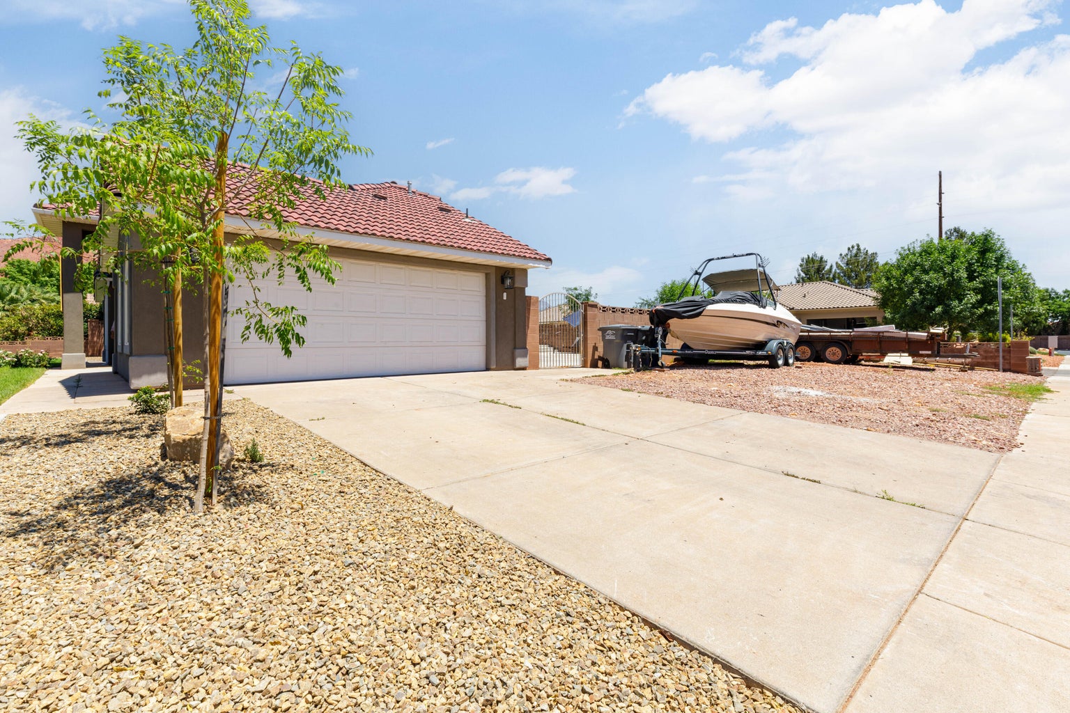 View of side of home featuring a garage, a tiled roof, driveway, and stucco siding