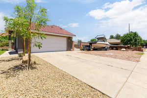 View of side of home featuring a garage, a tiled roof, driveway, and stucco siding