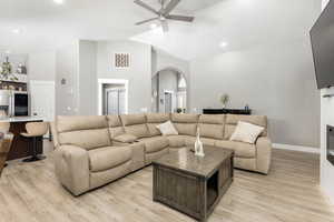 Living area featuring vaulted ceiling, light wood-style floors, ceiling fan, arched walkways, and recessed lighting