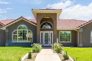 Doorway to property featuring a yard, stucco siding, and a tiled roof