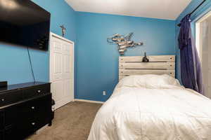 Bedroom with carpet flooring and vaulted ceiling