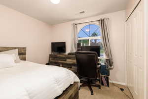 Carpeted bedroom with a closet and a desk