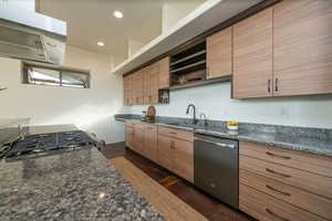 Kitchen with dark stone countertops, stainless steel appliances, extractor fan, recessed lighting, and modern cabinets