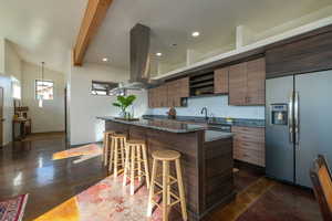 Kitchen featuring a breakfast bar, dark stone countertops, stainless steel appliances, island exhaust hood, and a center island