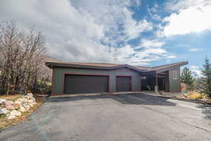 View of front of property with asphalt driveway, a shingled roof, and a garage