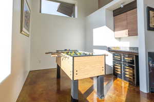 Playroom featuring beverage cooler, concrete floors, a bar, and a towering ceiling