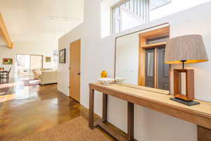 Hall with concrete floors, rail lighting, and vaulted ceiling