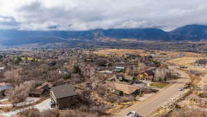 Aerial view of property and surrounding area featuring a mountain backdrop and nearby suburban area