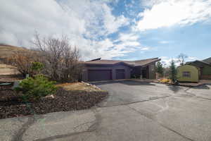 View of front of home featuring asphalt driveway, a garage, and a shingled roof