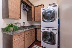 Washroom with cabinet space and stacked washer and clothes dryer