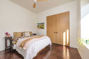 Bedroom featuring a closet, a ceiling fan, and finished concrete flooring