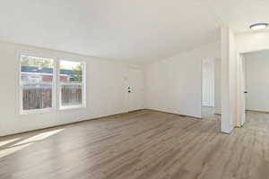 Unfurnished living room featuring light wood finished floors and a textured ceiling