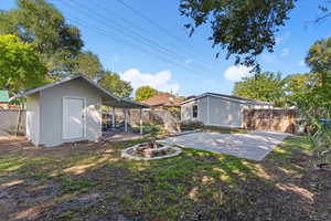 Back of house featuring a fenced backyard, a fire pit, a patio area, and an outbuilding