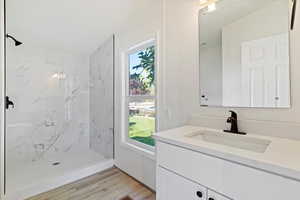 Full bathroom with vanity, a marble finish shower, and light wood-style floors