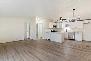 Kitchen featuring a chandelier, open floor plan, light countertops, white cabinetry, and hanging light fixtures