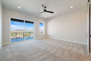 Unfurnished room with a mountain view, light colored carpet, a ceiling fan, recessed lighting, and a barn door