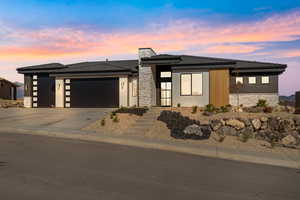 Prairie-style house featuring stone siding, a garage, and driveway