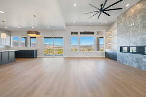Unfurnished living room with a mountain view, light wood-type flooring, healthy amount of natural light, built in shelves, and recessed lighting