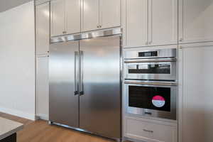 Kitchen with stainless steel appliances, light wood-style floors, and gray cabinets