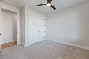 Unfurnished bedroom with a closet, carpet flooring, and ceiling fan
