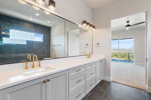 Full bathroom with double vanity, tiled shower, a mountain view, dark marble finish floors, and a ceiling fan