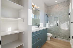 Bathroom featuring vanity, light wood-style floors, and a shower stall