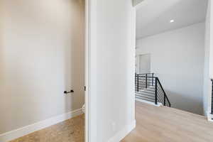 Corridor featuring an upstairs landing and recessed lighting