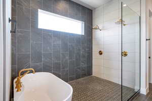Bathroom featuring a soaking tub, a shower stall, and dark tile patterned flooring