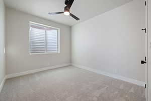 Empty room featuring light colored carpet and ceiling fan
