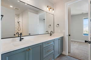 Bathroom with double vanity, dark colored carpet, and a shower