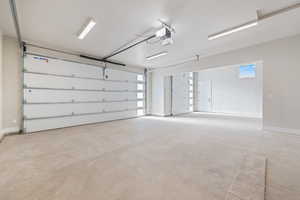 Garage featuring baseboards and a garage door opener