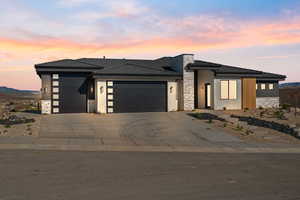 Prairie-style house featuring stone siding, an attached garage, concrete driveway, stucco siding, and a tile roof