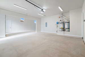 Garage with strapped water heater, electric panel, and a garage door opener