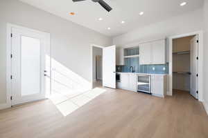 Kitchen featuring white cabinetry, light wood finished floors, beverage cooler, and recessed lighting