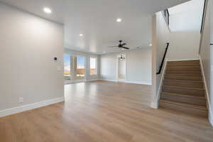 Unfurnished living room with stairs, light wood finished floors, recessed lighting, and ceiling fan