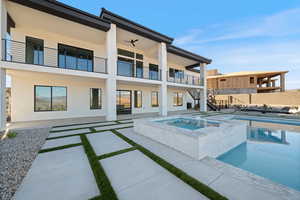 View of pool featuring stairs, a patio area, a pool with connected hot tub, and a balcony