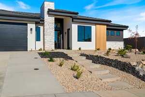 Prairie-style home featuring stone siding, stucco siding, concrete driveway, and an attached garage