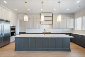 Kitchen with a spacious island, appliances with stainless steel finishes, decorative backsplash, hanging light fixtures, and recessed lighting