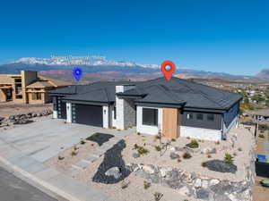 View of front of property featuring a mountain view, stone siding, concrete driveway, a garage, and stucco siding
