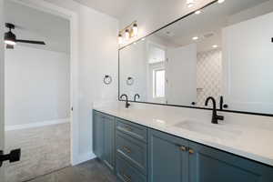 Full bath with double vanity, dark carpet, and ceiling fan