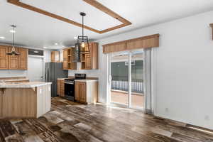 Kitchen with a breakfast bar, appliances with stainless steel finishes, a peninsula, pendant lighting, and dark wood finished floors