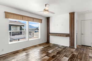 Unfurnished room featuring dark wood-style flooring, a mountain view, and a ceiling fan