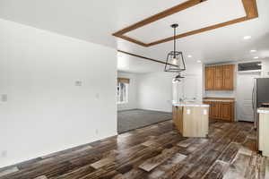 Kitchen featuring open floor plan, recessed lighting, a kitchen island with sink, decorative light fixtures, and freestanding refrigerator