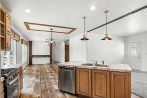 Kitchen featuring brown cabinetry, a kitchen island with sink, stainless steel appliances, hanging light fixtures, and recessed lighting
