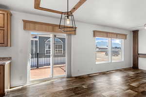 Unfurnished dining area with dark wood-style floors and baseboards