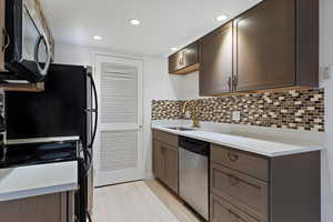 Kitchen featuring black range with electric cooktop, dishwasher, light stone counters, dark brown cabinets, and decorative backsplash