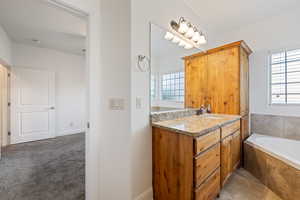 Full bathroom featuring vanity, a garden tub, and light carpet