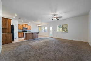 Kitchen with open floor plan, recessed lighting, a chandelier, a center island with sink, and light carpet