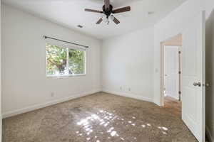 Carpeted spare room with baseboards and ceiling fan