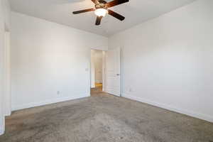Carpeted empty room featuring a ceiling fan and baseboards
